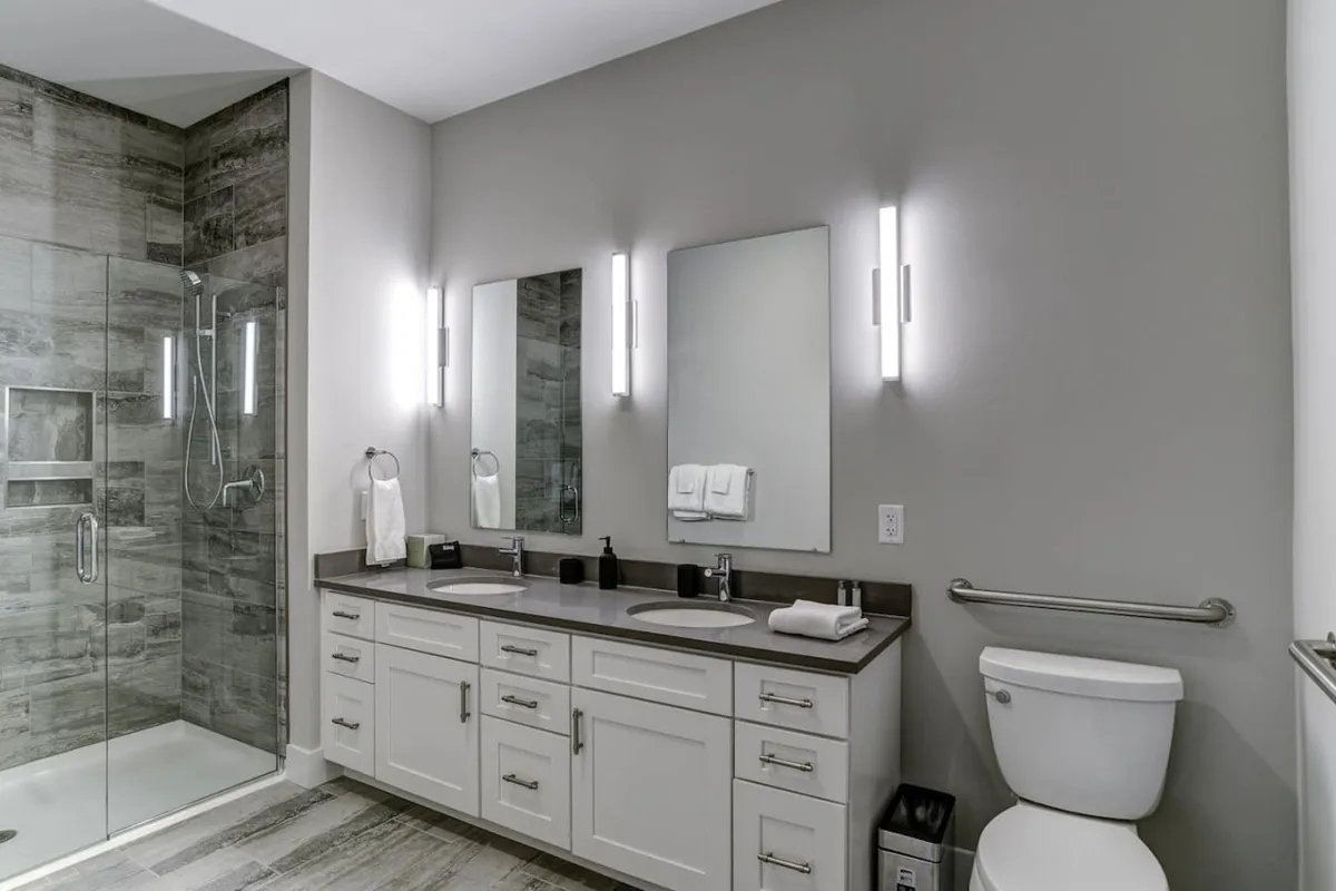 A contemporary ensuite bathroom featuring a double vanity with sinks, modern mirrors, and a spacious walk-in shower. The soft lighting and sleek finishes create a spa-like environment perfect for relaxation and self-care.