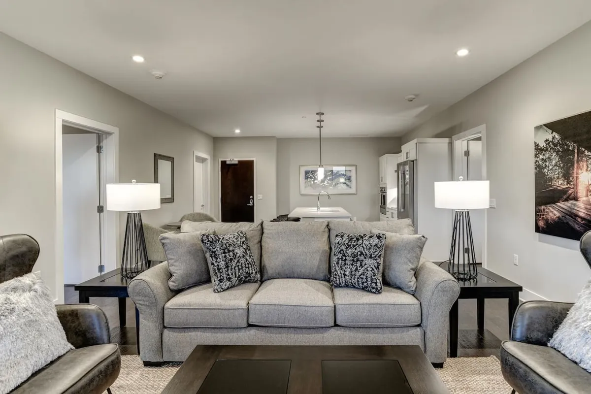 This image features another angle of the living area, focusing on a plush sofa with decorative pillows, ambient lighting from table lamps, and vibrant artwork. The space exudes warmth and invitation, promoting both relaxation and casual work sessions.