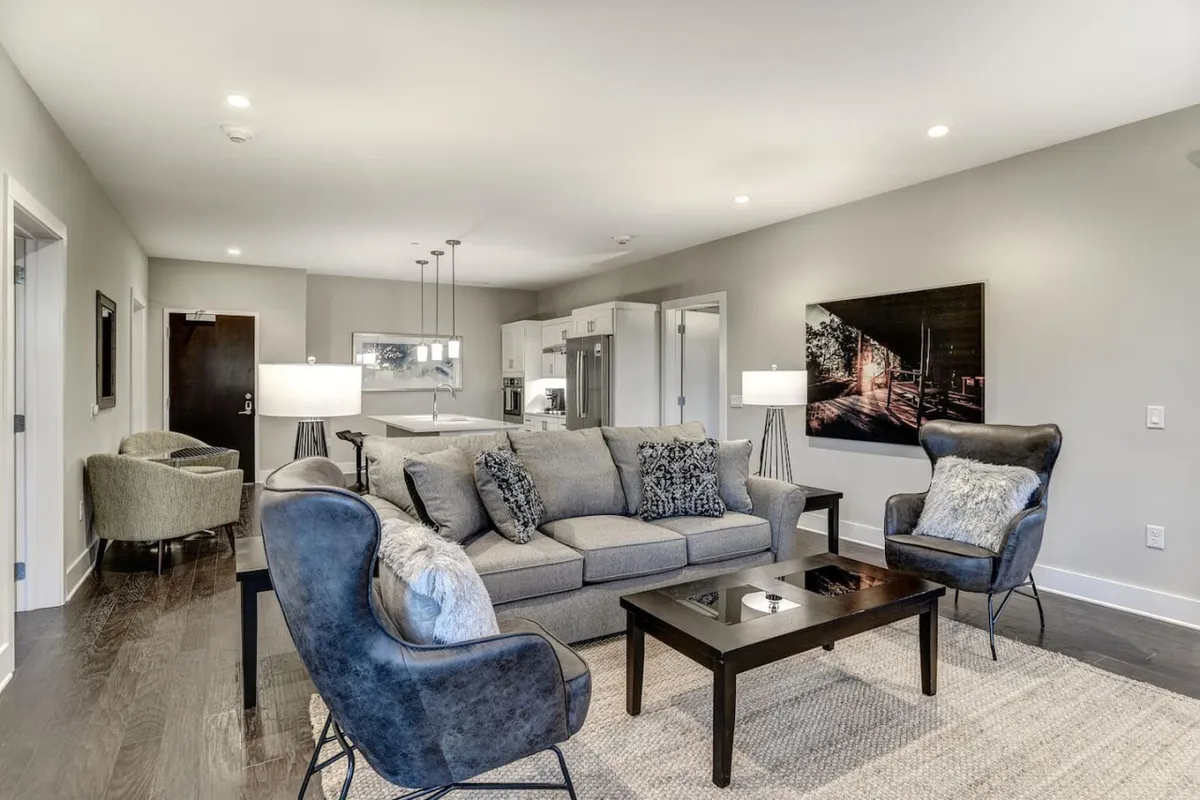 A comfortable living area with a plush sofa, armchairs, a coffee table, and tasteful artwork. The space feels inviting, ideal for relaxing, socializing, or hosting small gatherings before heading out or returning from a night in Asheville.